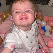 Willow is registered to the contest to win money with this photo: baby, child, toddler, smiling, pink_tutu, bib, plastic_balls, ball_pit, indoor, happy, cute, face, person, clothing, sitting, playtime, hair_tie, toy, fun, celebration