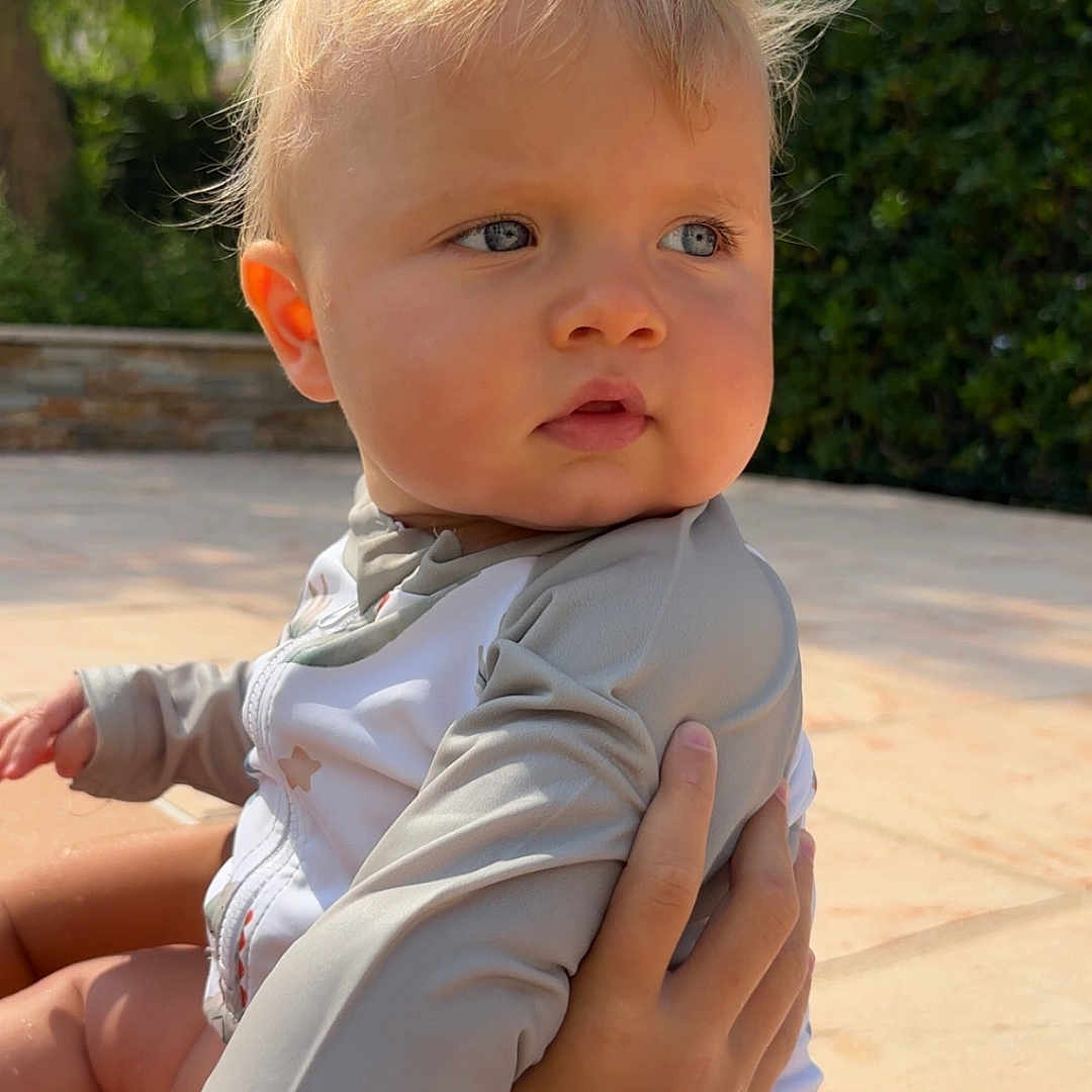 Andréa a rejoint le concours — aidez-le/la à gagner de superbes lots ! baby, blonde_hair, blue_eyes, child, clothing, cute, daylight, expression, face, garden, hand, nature, outdoor, person, portrait, sitting, skin, summer, sunlight, young_child
