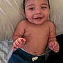 baby, child, smiling, shirtless, pants, bed, pillow, happy, infant, cute, skin, hand, face, head, lying_down, young_child, indoors, comfort, relaxed, sleepwear