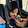 Carmelo is registered to the contest to win money with this photo: baby, car_seat, child, toy, snack, car_interior, seatbelt, smiling, infant, foot, clothing, window, door, plastic_container, striped_shirt, happy, sitting, inside, child_safety, cute