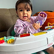 Vanellope joined the competition — help win amazing prizes! baby, infant, child, pacifier, toy, activity_seat, purple, pink_clothing, couch, plush_toy, orange, indoor, person, cute, smiling, playful, face, hand, foot, hair