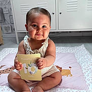 Aliyah participe au concours pour gagner de l'argent avec cette photo : baby, infant, milestone_card, sitting, cute, nursery, soft_toy, plush, floor_mat, child, indoors, smiling, portrait, clothing, hands, feet, face, decor, room, person