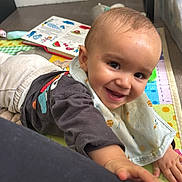Elyo a rejoint le concours — aidez-le/la à gagner de superbes lots ! baby, bib, book, child, clothing, colorful, crawling, cute, face, floor, hand, happy, head, indoor, person, play_mat, reaching, smiling, toy, young_child