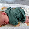 baby, sleeping, green_clothing, diaper, blanket, crib, infant, teddy_bear_pattern, soft_texture, cute, peaceful, child, indoors, rest, cozy, sock, newborn, nap, cute_clothing, baby_bedding