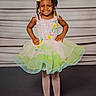 child, girl, smiling, dress, colorful, tutu, posing, happy, curly_hair, flower_hair_accessory, tights, ballet_shoes, studio, portrait, standing, confident, cute, fashion, young, background