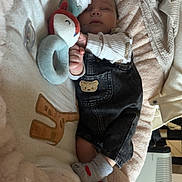 Evan a rejoint le concours — aidez-le/la à gagner de superbes lots ! baby, sleeping, plush_toy, blanket, denim_overalls, socks, cozy, cute, indoor, soft, comfort, child, resting, peaceful, warm, cuddle, heart_doodle, fabric, furniture, infant