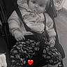 toddler, child, stroller, jacket, pacifier, pants, patterned_pants, sitting, indoor, floor, baby, cute, face, expression, footwear, socks, seatbelt, black_and_white, heart_emoji, curious