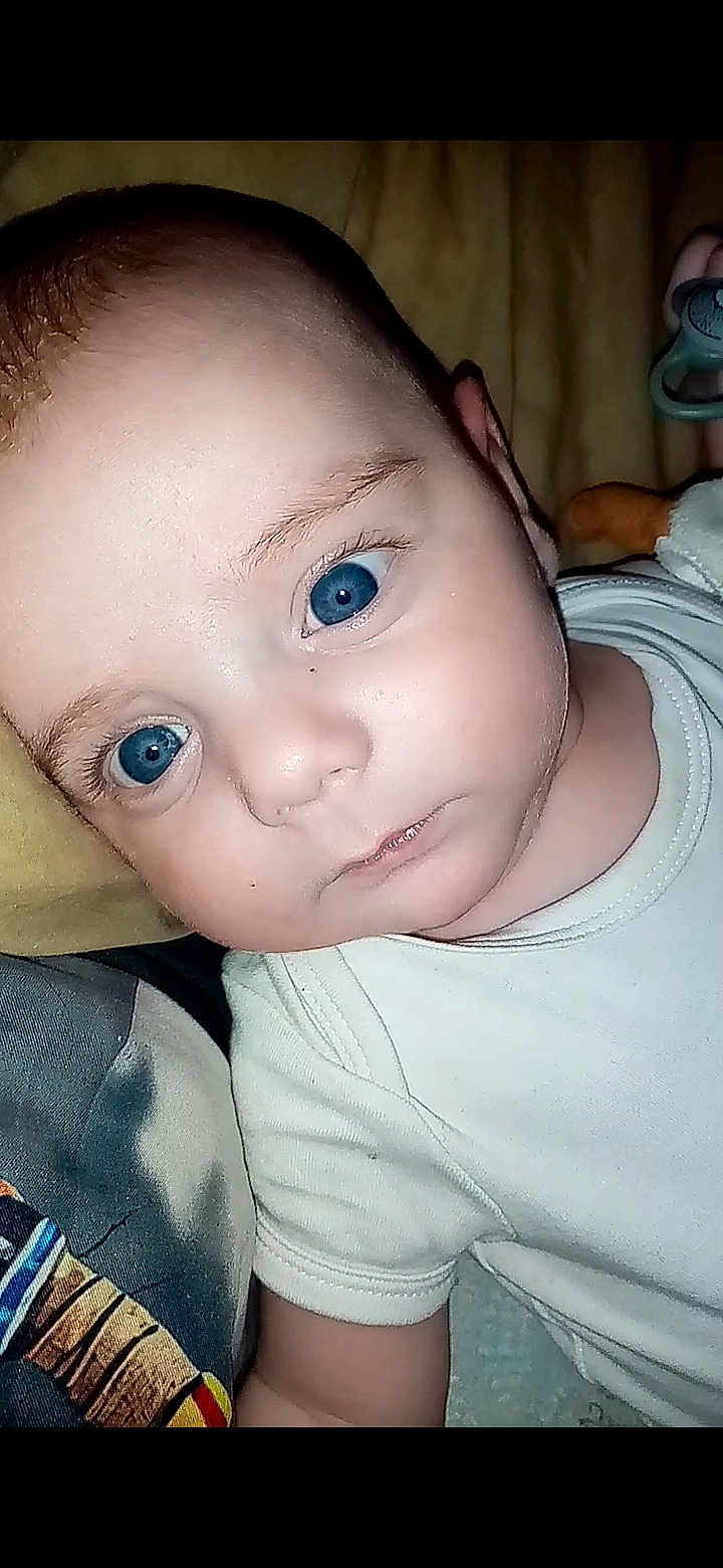 Lucas participe au concours pour gagner de l'argent avec cette photo : baby, blue_eyes, close_up, face, infant, laying_down, pacifier, person, portrait, skin, white_shirt, young_child, child, cute, expressionless, indoor, blanket, hand, head, eyebrows