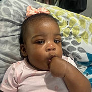 Aleiyah is registered to the contest to win money with this photo: baby, child, infant, pink_dress, bow, blanket, hand, thumb, face, skin, lying_down, indoors, person, closeup, cute, young_child, expression, apparel, head, sleepwear