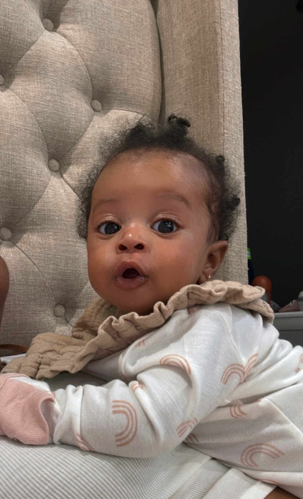 Amari joined the competition — help win amazing prizes! baby, infant, child, face, eyes, clothing, pajamas, fabric, cushion, chair, curly_hair, expression, cute, indoors, portrait, skin, hand, lying_down, soft_lighting, cozy