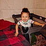 toddler, child, playpen, bed, blanket, curly_hair, smiling, indoor, person, fabric, bedroom, happy, clothing, colorful, quilt, furniture, baby, hands, face, home