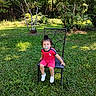 toddler, child, pacifier, chair, grass, outdoor, nature, trees, greenery, funny_face, red_clothing, white_shoes, sunlight, summer, playful, young_child, sitting, casual, daytime, backyard