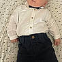 Andréas a rejoint le concours — aidez-le/la à gagner de superbes lots ! baby, infant, child, face, clothing, white_shirt, dark_pants, lying_down, patterned_bed_sheet, curious_expression, wide_eyes, indoor, soft_lighting, cute, small_hands, socks, casual_wear, portrait, young_child, head