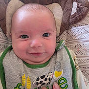 Jackson Jandrin joined the competition — help win amazing prizes! adult_hand, animal_print, baby, bedding, bib, blanket, child, close_up, clothing, cow_design, cozy, cuddly_toy, eyes, face, green_trim, indoors, infant, photography, portrait, smiling
