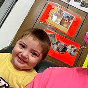 Kaycen joined the competition — help win amazing prizes! child, smiling, yellow_shirt, indoor, wood_panel_wall, photo_collage, happy, person, portrait, candid, home, casual, face, young_child, seated, colorful, wall_decor, family_photos, interior, people
