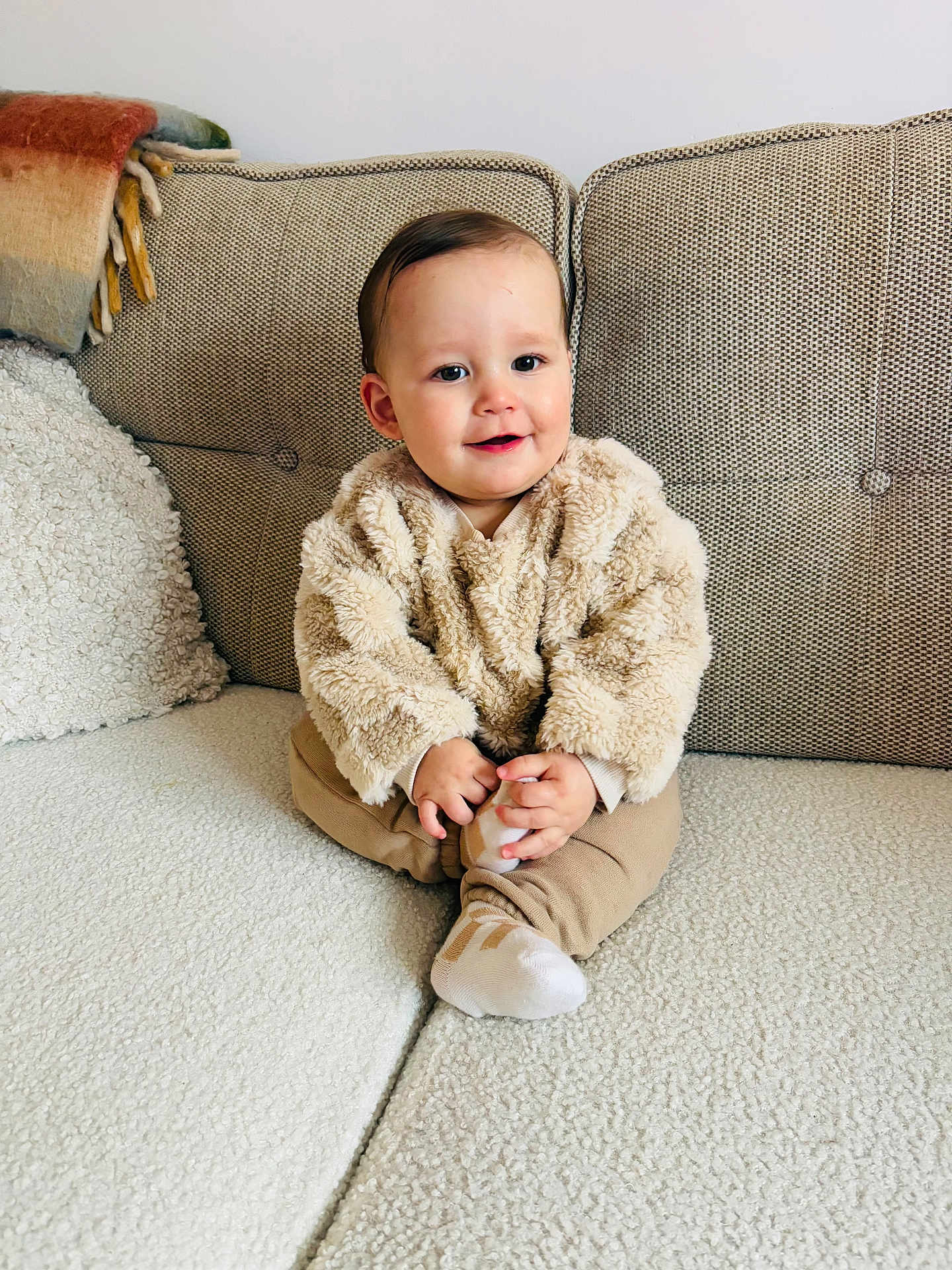 Leo joined the competition — help win amazing prizes! baby, child, couch, sweater, beige, smile, home, cozy, furniture, sitting, infant, cute, warm, blanket, cushion, portrait, person, indoor, comfortable, happy