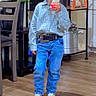 basket, belt, blue_jeans, casual, chair, child, cowboy_hat, flower, houseplant, indoor, juice_box, kitchen, plaid_shirt, portrait, pot, shelf, shoes, standing, wooden_floor, young_boy