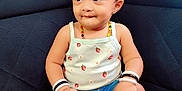 Luvella is registered to the contest to win money with this photo: toddler, child, headband, bow, tank_top, strawberry_pattern, denim_shorts, socks, bracelets, cross_legged, couch, black_couch, indoor, cute, portrait, sitting, curious, young_child, person, baby