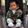 baby, car_seat, child, infant, clothing, green, striped_pants, white_socks, black_hair, face, seatbelt, indoor, floor, safety, cute, young_child, portrait, graco, snugride, casual