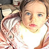 toddler, child, blue_eyes, pigtails, yellow_bows, pink_jacket, white_sweater, blue_pants, indoor, wooden_floor, basket, oranges, glass_jar, curious, portrait, cute, young_child, person, sitting, casual_clothing