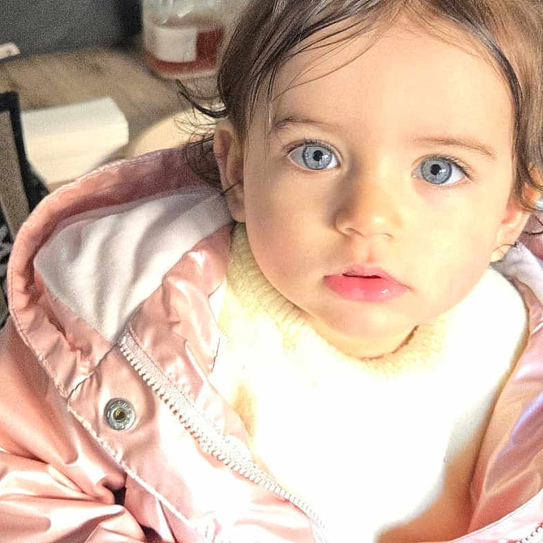 Jana participe au concours pour gagner de l'argent avec cette photo : toddler, child, blue_eyes, pigtails, yellow_bows, pink_jacket, white_sweater, blue_pants, indoor, wooden_floor, basket, oranges, glass_jar, curious, portrait, cute, young_child, person, sitting, casual_clothing