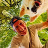 Tom a rejoint le concours — aidez-le/la à gagner de superbes lots ! man, dog, smile, tongue_out, cap, outdoor, nature, tree, greenery, sunlight, happy, pet, animal, portrait, leisure, canopy, daylight, friendship, casual_clothing, closeup