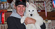 Tom a rejoint le concours — aidez-le/la à gagner de superbes lots ! man, dog, white_dog, trophy, medal, ribbon, cap, sunglasses, smile, indoor, shelf, award, portrait, pet, holding, proud, fluffy, animal, person, celebration