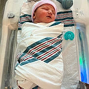 Jimmy is registered to the contest to win money with this photo: newborn, baby, infant, sleeping, swaddled, hospital, bassinet, blanket, striped_cap, pacifier, medical_equipment, nursery, portrait, face, closed_eyes, peaceful, lying_down, indoors, healthcare, striped_blanket