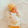 advertisement, baby, bodypart, bonnet, cap, clothing, face, finger, glove, hand, hat, head, newborn, pants, person, photography, portrait, poster, sleeping, text