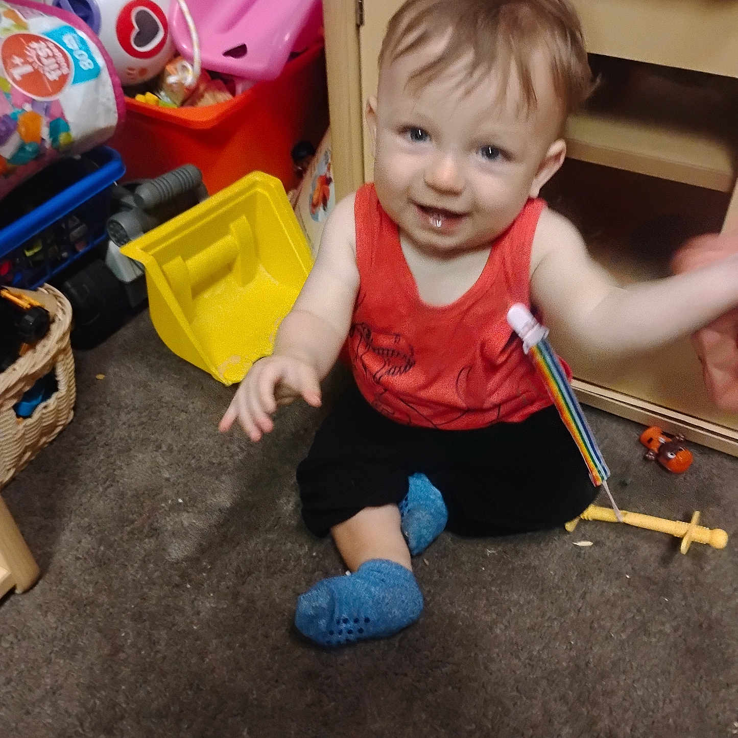 Arkadian joined the competition — help win amazing prizes! baby, basket, blue_socks, carpet, child, colorful, cute, face, floor, furniture, hand, happy, indoor, plastic_toy, playroom, red_shirt, sitting, smiling, toddler, toy