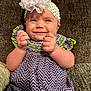 baby, smile, headband, flower, dress, purple, green, zigzag_pattern, hands, fists, couch, texture, infant, happy, portrait, sitting, cute, child, apparel, indoor