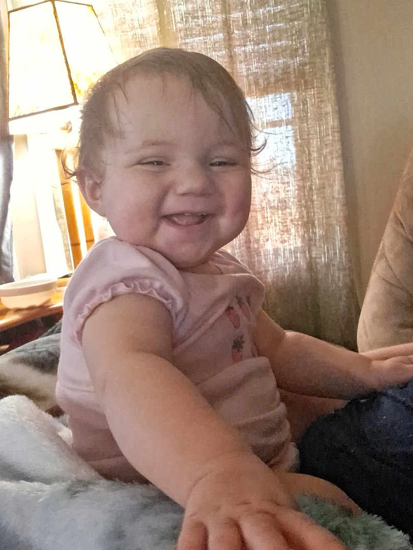 Madilynn joined the competition — help win amazing prizes! baby, child, smiling, happy, indoor, lamp, blanket, curtain, person, toddler, clothing, hand, face, furniture, cozy, portrait, sitting, cute, infant, home