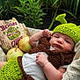 Everett is registered to the contest to win money with this photo: baby, crochet, green_hat, brown_vest, blanket, outdoor, plants, onions, wooden_sign, shrek_theme, infant, cute, costume, portrait, lying_down, face, handmade, nature, funny, child