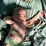 baby, infant, blanket, plush_toy, dinosaur, sunlight, shadow, skin, diaper, knitwear, resting, texture, green, soft_light, peaceful, cute, child, indoor, relaxed, portrait