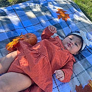 Emma is registered to the contest to win money with this photo: baby, infant, child, plaid_blanket, autumn_leaves, pumpkin, headband, outdoor, grass, fall, cute, portrait, lying_down, orange_clothing, seasonal, nature, smiling, baby_clothes, head, skin