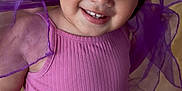 Sloane is registered to the contest to win money with this photo: toddler, child, smiling, pink_top, white_tights, purple_fabric, indoor, wooden_floor, portrait, playful, happy, small_earrings, cute, young_child, girl, closeup, bright_eyes, fashion, person, cheerful