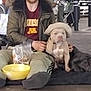 man, dog, hat, sitting, parking_garage, people, car, jacket, pants, leash, plastic_bag, bowl, concrete_floor, shopping_cart, woman, child, urban, casual_clothing, indoor, companionship