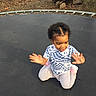 toddler, child, trampoline, outdoor, yard, leaves, logs, tree, clothing, smile, happy, sitting, person, play, casual, nature, sunlight, short_hair, footwear, fun