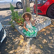 Giulia a rejoint le concours — aidez-le/la à gagner de superbes lots ! toddler, child, curly_hair, sunhat, green_dress, rock, parking_lot, concrete_curb, car, shadow, tree, summer, outdoor, asphalt, plant, sidewalk, footwear, sandals, casual, curiosity