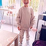 blanket, casual_clothing, child, cozy, curtains, daylight, floor, furniture, happy, heart_overlay, high_chair, indoor, light_effect, playpen, smiling, sneakers, standing, table, window, young