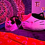 cat, plush_toy, bed, blanket, heart_pattern, mandala_tapestry, wall_art, purple_lighting, pink_lighting, indoor, cozy, feline, decor, soft_toy, relaxed, pet, colorful, cushion, furniture, room