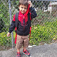 Ezra joined the competition — help win amazing prizes! child, boy, hoodie, spiderman, sneakers, backpack, sidewalk, fence, greenery, outdoor, casual, shorts, playful, portrait, standing, young, person, smiling, daylight, urban