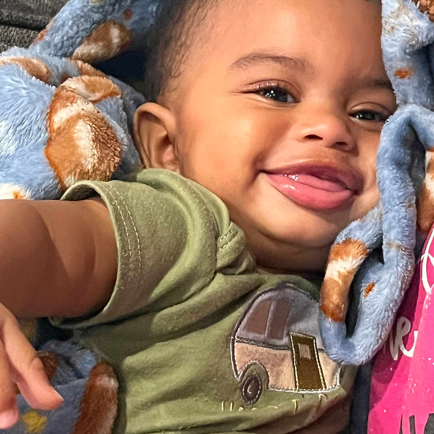 Jalen Malik Scott Jr joined the competition — help win amazing prizes! baby, child, infant, portrait, smiling, tongue_out, close_up, blanket, cozy, indoor, lying_down, green_shirt, vehicle_graphic, blue_blanket, happy, face, eyes, hair, baby_clothing, home