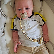 Maylan a rejoint le concours — aidez-le/la à gagner de superbes lots ! baby, infant, pacifier, clothing, polo_shirt, pants, beads, toy, stuffed_animal, baby_seat, cushion, face, hand, person, comfort, indoor, child, cute, relaxing, closeup