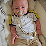 baby, infant, pacifier, clothing, polo_shirt, pants, beads, toy, stuffed_animal, baby_seat, cushion, face, hand, person, comfort, indoor, child, cute, relaxing, closeup
