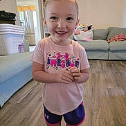 Amara joined the competition — help win amazing prizes! casual_clothing, child, couch, daylight, floor, furniture, girl, happy, home, indoor, laundry_basket, living_room, person, pink_shirt, portrait, shorts, smiling, toddler, wooden_floor, young_child