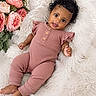 baby, infant, cute, smiling, pink_outfit, curly_hair, fluffy_blanket, flowers, portrait, child, indoors, relaxing, soft_texture, wooden_buttons, happy, lying_down, skin, natural_light, cozy, peaceful