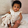 Amaris is registered to the contest to win money with this photo: baby, child, plush_bunny, knitted_blanket, pillows, curly_hair, sitting, indoors, cute, infant, neutral_colors, soft_toys, smiling, portrait, cozy, home, wooden_buttons, short_sleeves, barefoot, curious