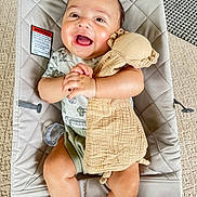 James joined the competition — help win amazing prizes! baby, smiling, infant, baby_seat, toy, pacifier, clothing, carpet, fabric, hand, face, cute, child, indoor, person, seat, happy, soft_toy, lying_down, blanket