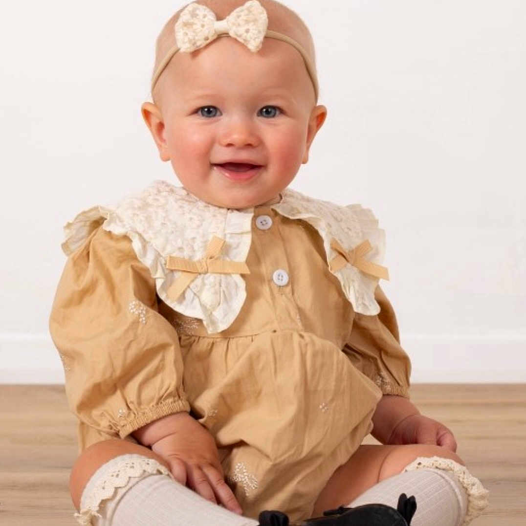 Melania is registered to the contest to win money with this photo: baby, child, collar, cute, dress, fashion, floor, happy, headband, indoor, infant, lace, person, portrait, shoes, sitting, smiling, socks, studio, young_child